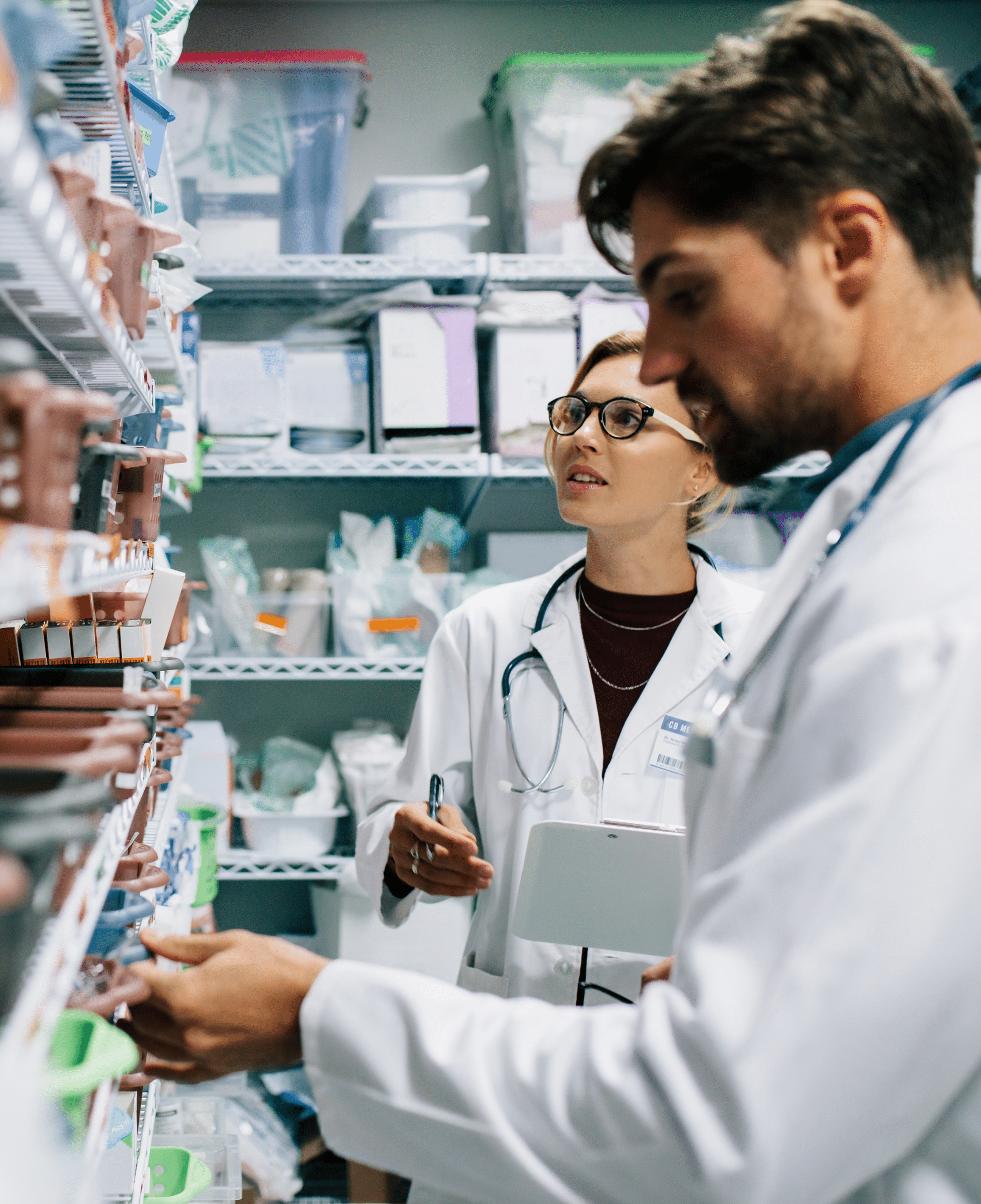 Two pharmacists look for something in a medication storage room
