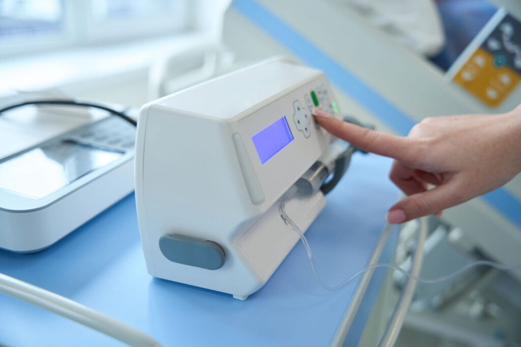 Close up of doctor hand adjusting syringe pump for anesthesia and drug administration during medical procedures in the intensive care unit.