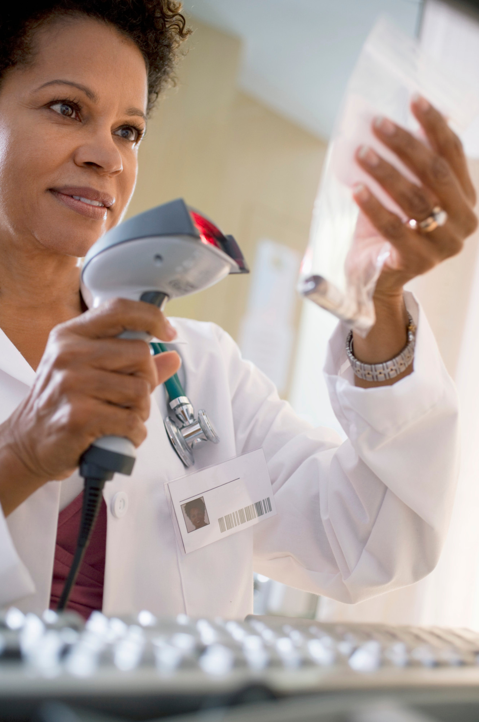 Pharmacist using a barcode scanner to identify a vial in a plastic bag.