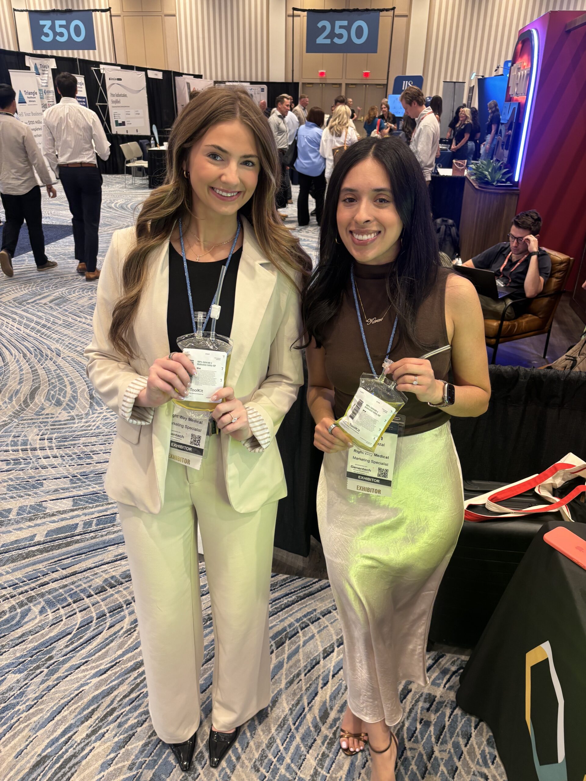 Two exhibitors enjoying RxToolKit's IV drink bags.