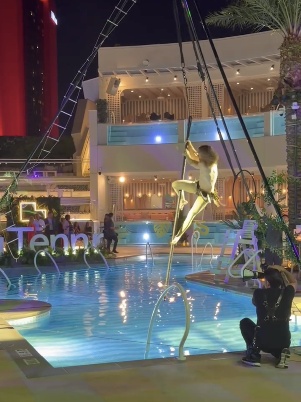 A man dressed as Tarzan swings from a pole over a pool.