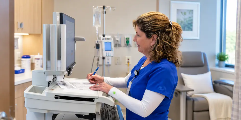 Blog RxToolKit Infusion nurse reviewing infusion medication protocols on a computer in an infusion center.